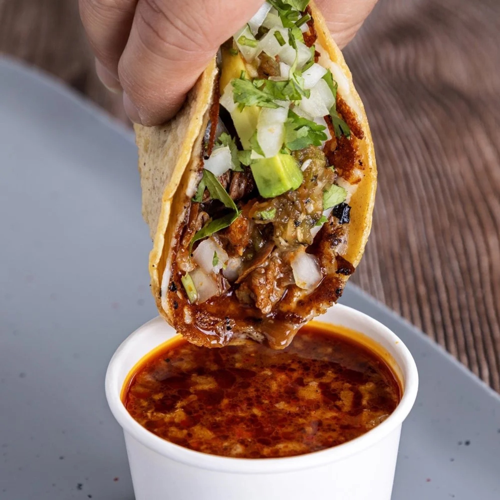 Birria taco being dipped into consomé from Spitfire.