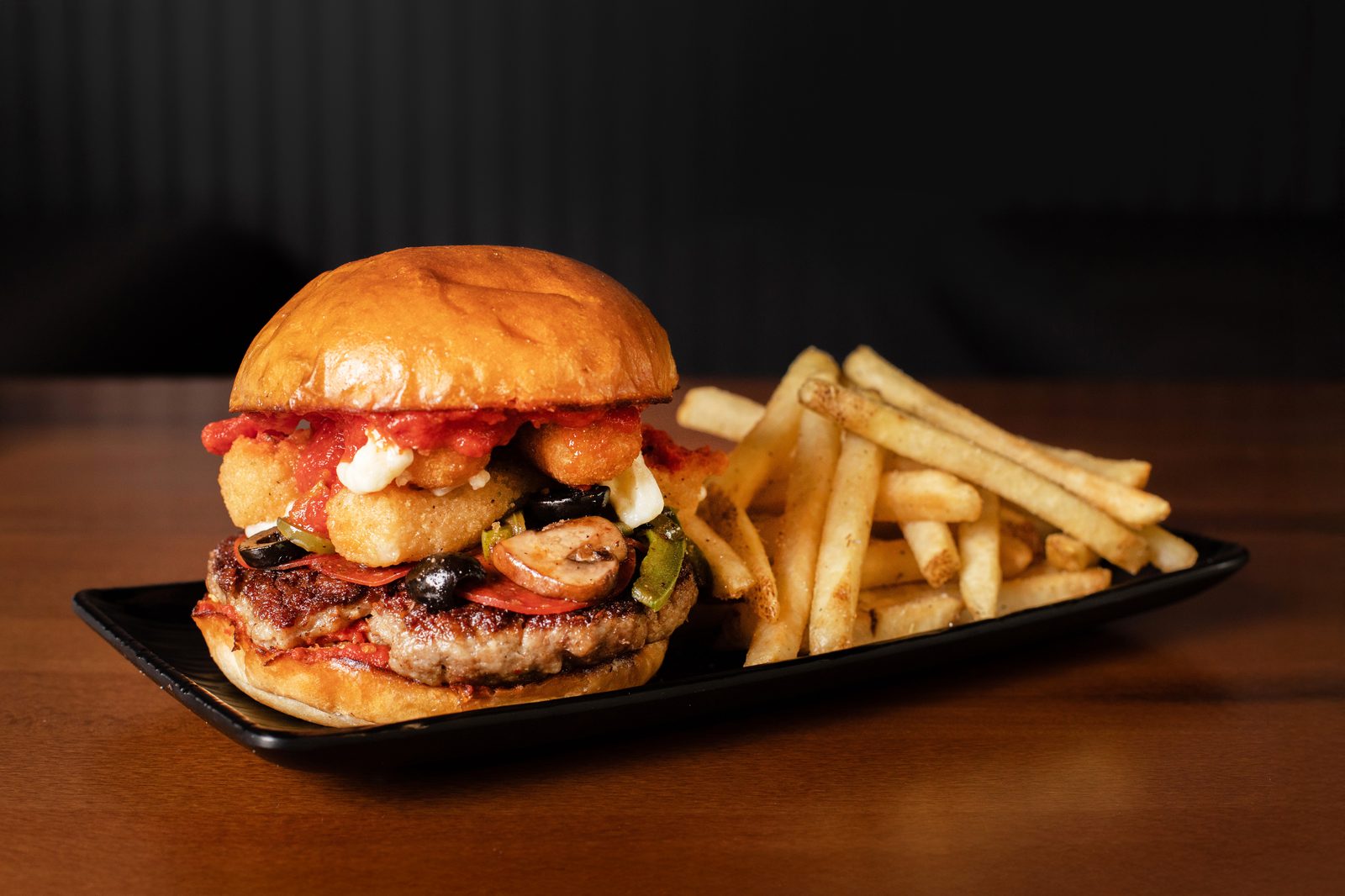 A Ground Rules smashburger with shredded lettuce and a side of seasoned fries.