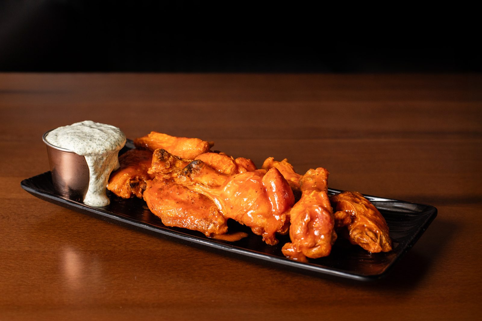 Hand-breaded, twice-fried wings glazed and stacked on a board.